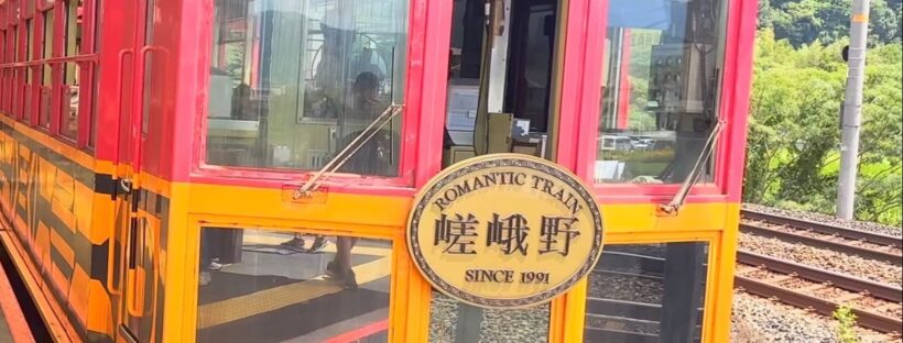 嵐山小火車紅黃色舊車廂車頭，掛著「嵯峨野 ROMANTIC TRAIN SINCE 1991」牌子