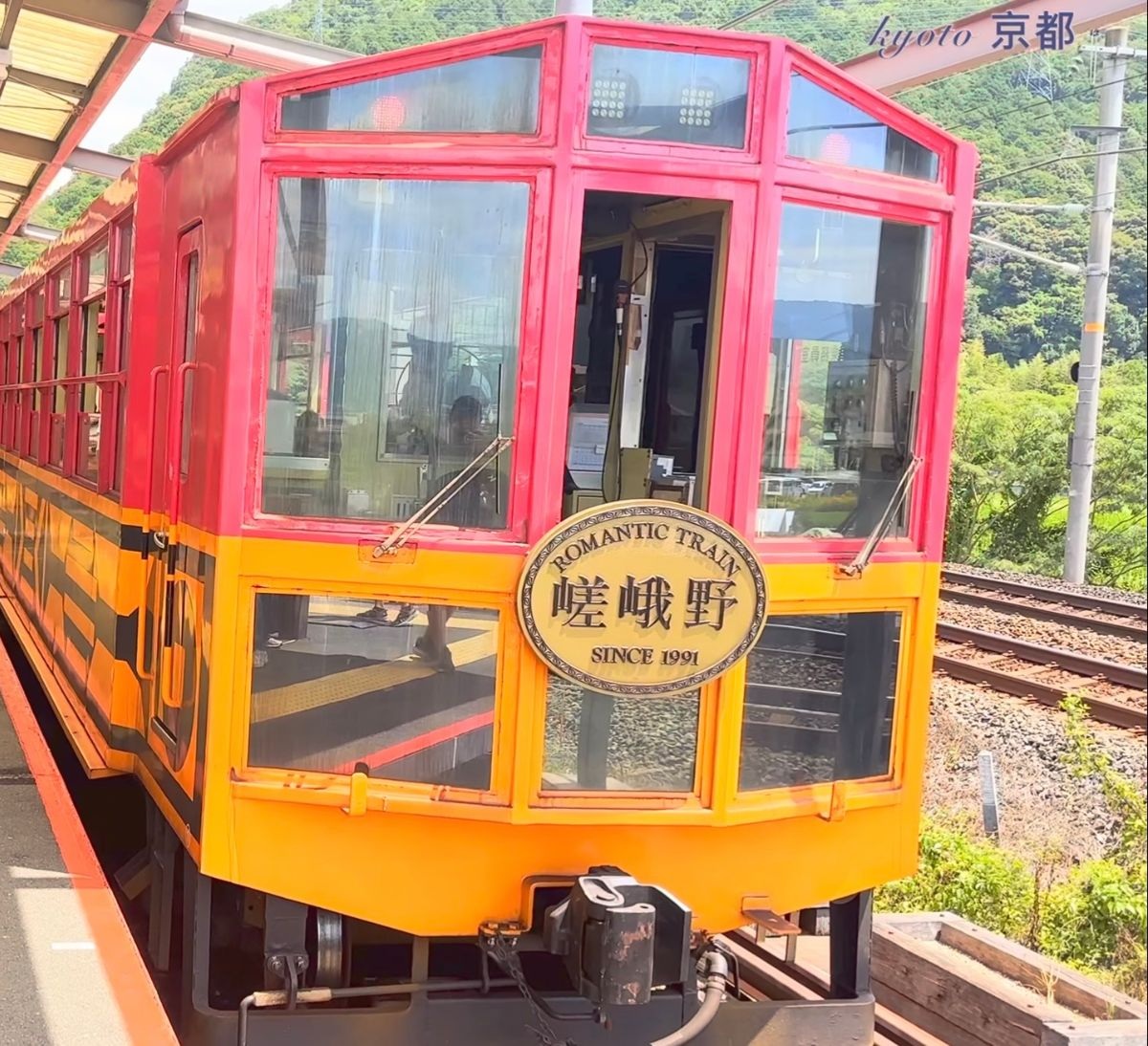 嵐山小火車紅黃色舊車廂車頭，掛著「嵯峨野 ROMANTIC TRAIN SINCE 1991」牌子
