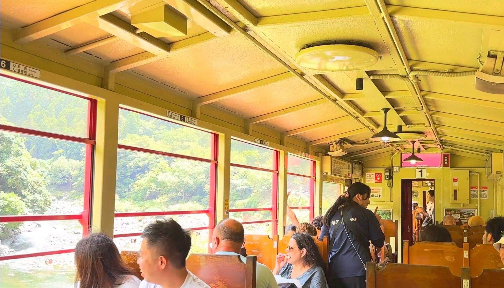 嵐山小火車舊車廂內部，木頭座椅與窗外的保津川